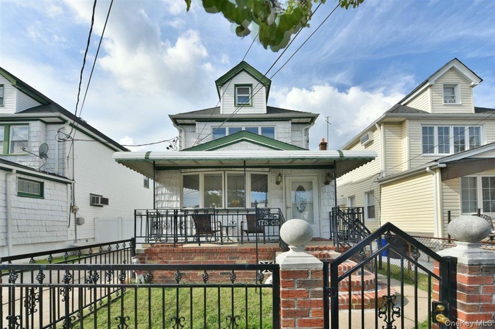 View of front of property featuring a fenced front yard, covered porch, and a gate