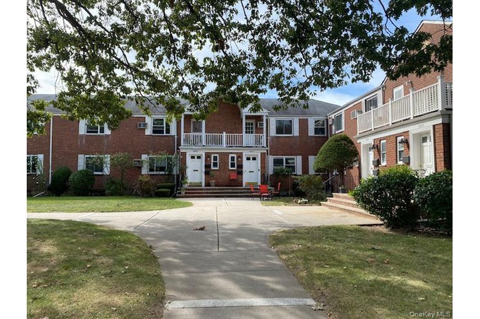 View of front of home featuring a balcony, brick siding, and a front lawn