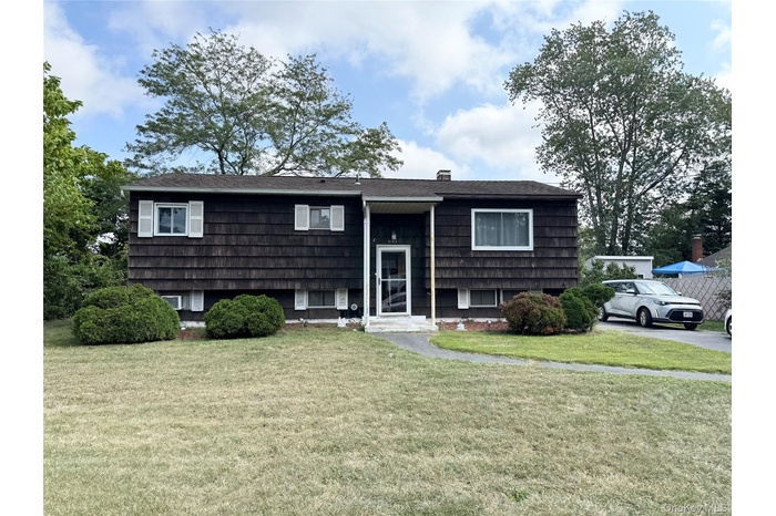Split foyer home featuring a front yard and a chimney