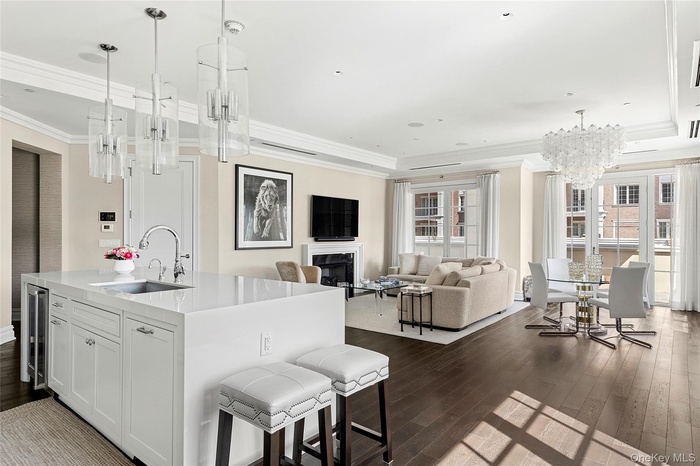 Kitchen with dark wood-type flooring, a notable chandelier, a sink, and crown molding