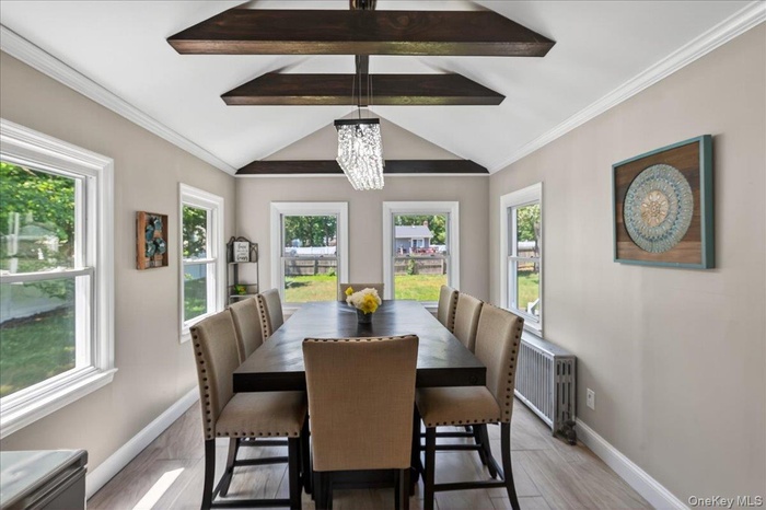 Dining space featuring crown molding, a chandelier, radiator, and light wood-style flooring