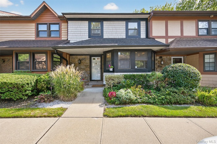View of front of property with stone siding, covered porch, and a shingled roof
