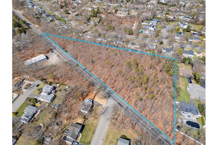 Aerial overview of property's location with nearby suburban area and property parcel outlined