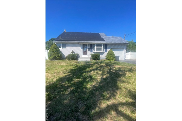 Single story home featuring an attached garage, roof mounted solar panels, and driveway