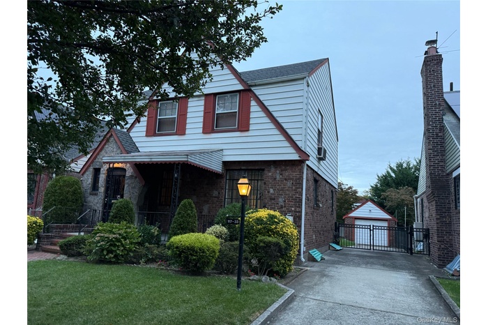 View of front of house featuring an outbuilding, brick siding, and a front yard