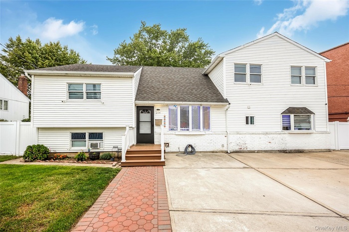 Split level home with roof with shingles and brick siding