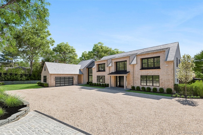 Contemporary home with a garage, gravel driveway, and brick siding