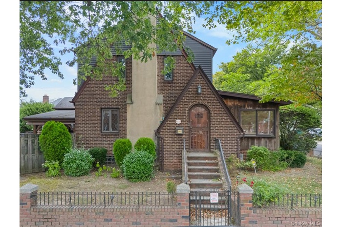 English style home featuring a fenced front yard, a gate, and brick siding