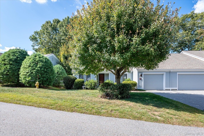Obstructed view of property with a front lawn, an attached garage, driveway, and roof with shingles