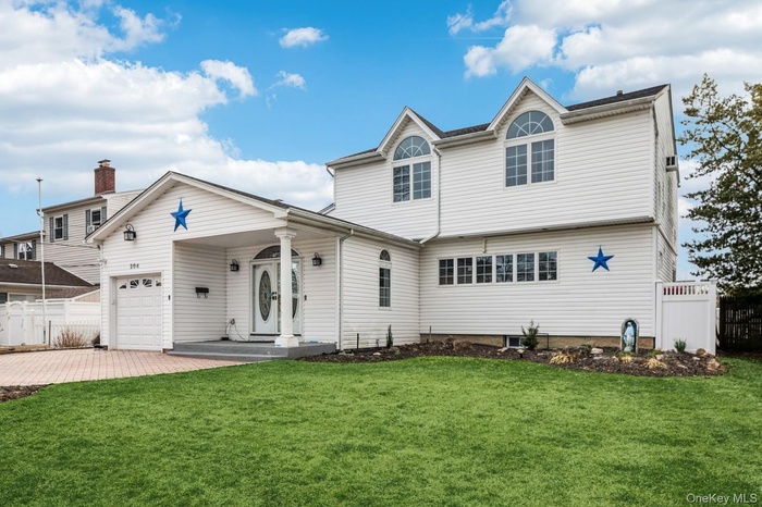 View of front of house featuring fence, driveway, a front lawn, and a garage
