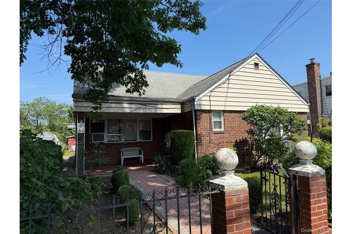 View of front of property with a porch, a gate, a fenced front yard, and brick siding