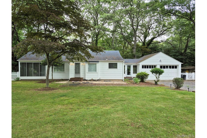 Ranch-style house featuring an attached garage, driveway, entry steps, a shingled roof, and a sunroom