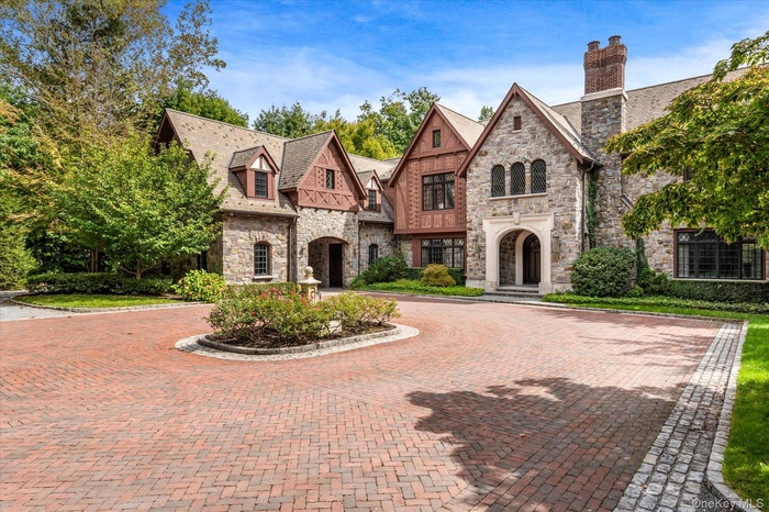 French country style house featuring stone siding, curved driveway, and a high end roof