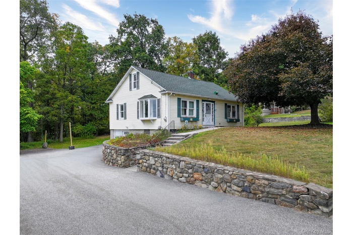 View of front of home with a front lawn, a chimney, and a shingled roof