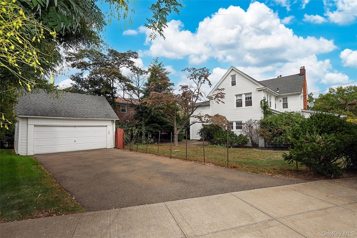 View of side of home with an outbuilding, a garage, a yard, and a shingled roof