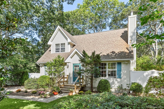 Cape cod-style house with roof with shingles and a chimney