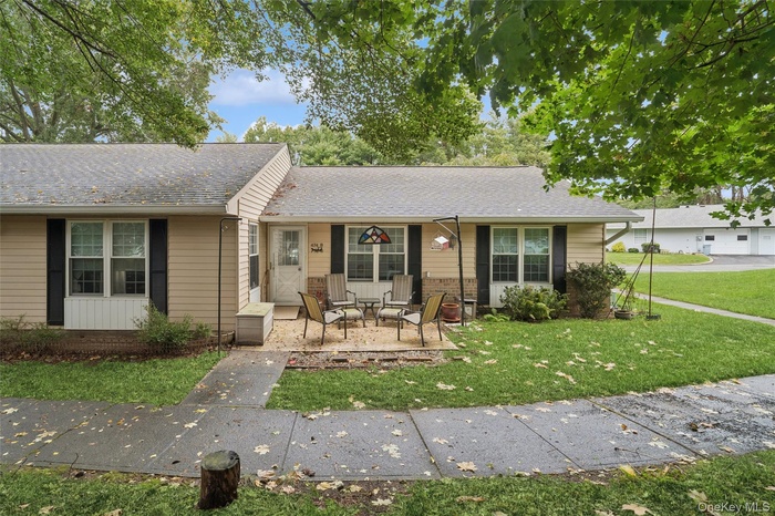 Ranch-style house featuring roof with shingles, covered porch, and a front yard