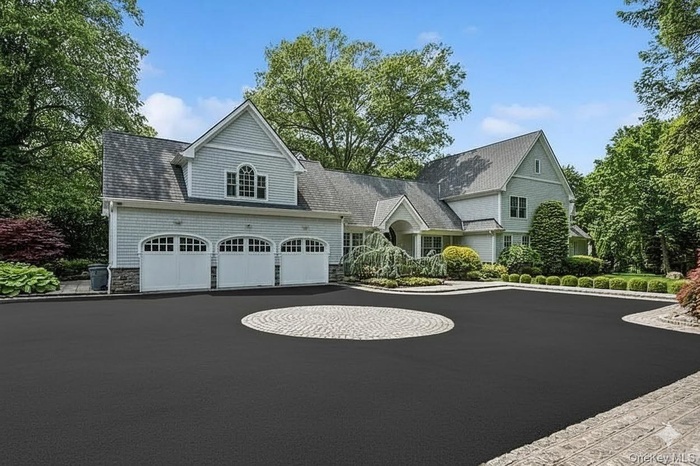 View of front facade featuring driveway, a garage, and a shingled roof