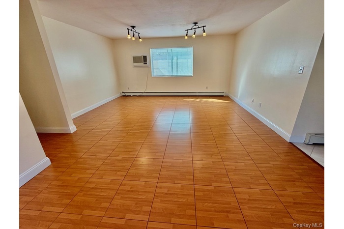 Spare room featuring a baseboard heating unit and a wall mounted air conditioner