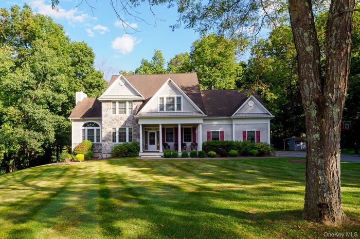 View of front facade featuring a porch, stone siding, a front yard, and a chimney