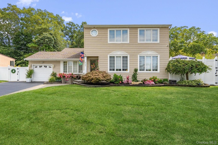 Colonial home featuring a garage, asphalt driveway, and a gate