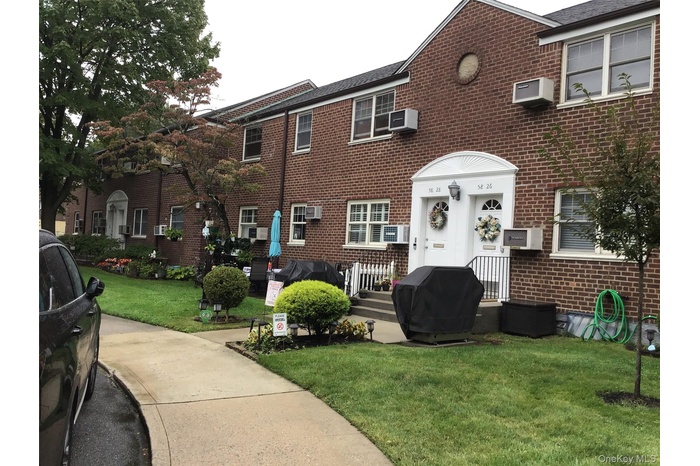 View of front of property with a front lawn, brick siding, and a wall mounted air conditioner