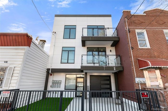 View of front of property with a balcony, stucco siding, a fenced front yard, and a gate