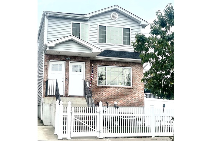 Traditional-style house featuring a fenced front yard, brick siding, and a gate