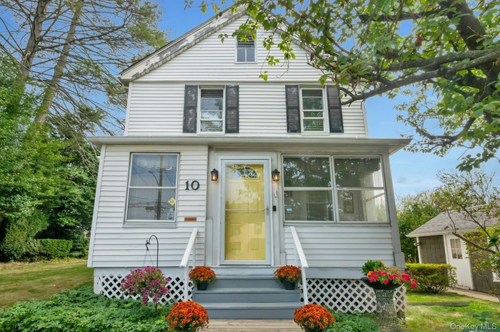Charming colonial curb appeal with enclosed front porch and welcoming entry framed by seasonal plantings.