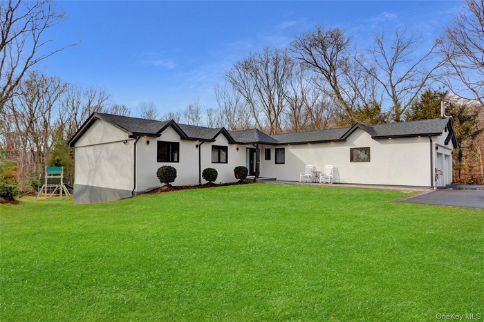 View of front of home featuring a front lawn, stucco siding, and a shingled roof