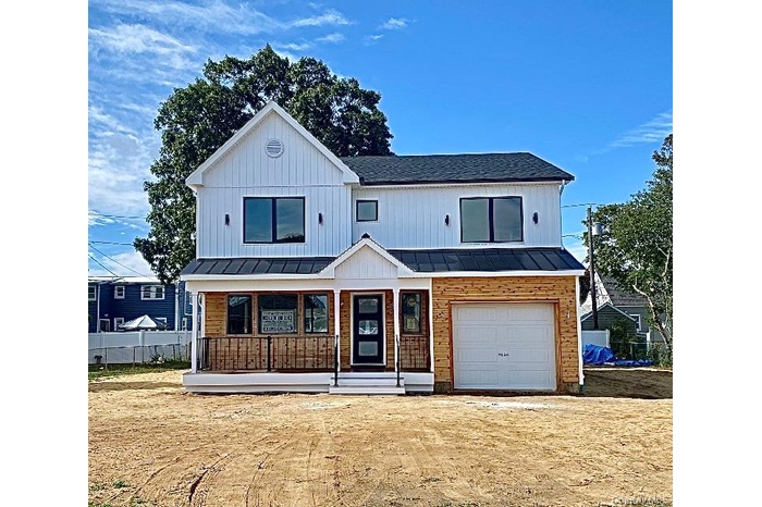 View of front of property featuring a porch, a standing seam roof, an attached garage, a metal roof, and a shingled roof