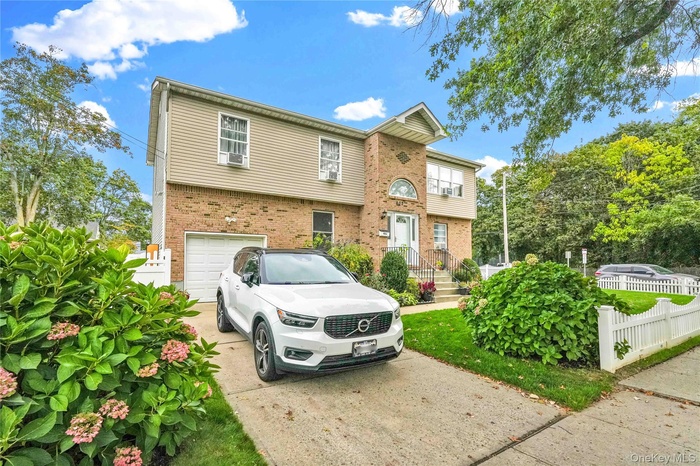 Colonial home with driveway, brick siding, and a garage