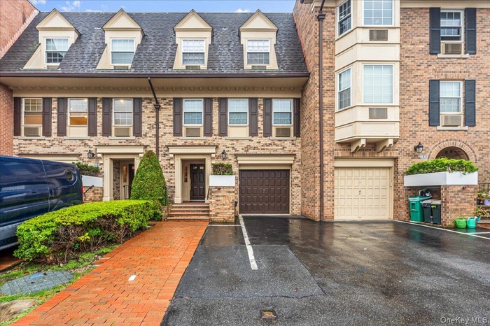 View of front of home with driveway, brick siding, and a garage