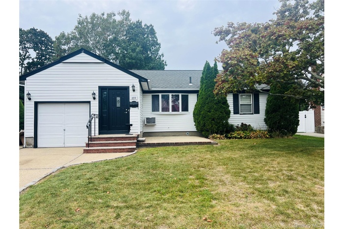 Single story home featuring a front yard, a shingled roof, and driveway