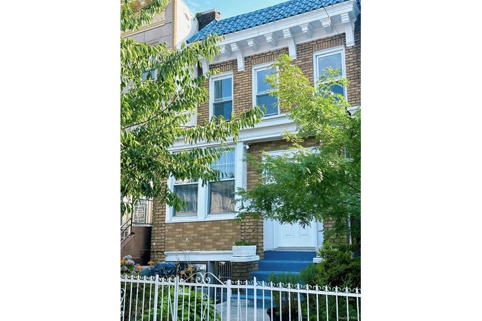 View of side of home with brick siding, a fenced front yard, a tiled roof, and a chimney