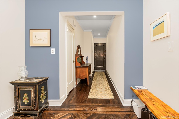 Corridor with dark wood-type flooring, ornamental molding, and recessed lighting