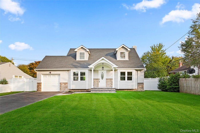 Cape cod-style house featuring stone siding, asphalt driveway, a shingled roof, a garage, and a chimney