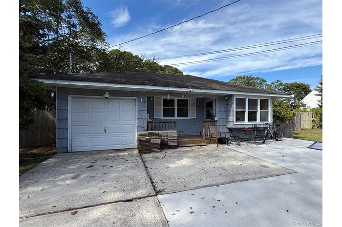 Ranch-style house featuring a porch, a shingled roof, driveway, and an attached garage