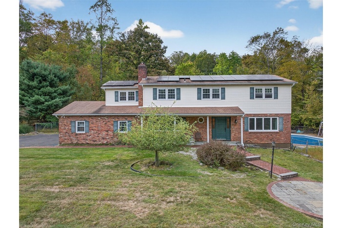 Traditional home featuring a chimney, brick siding, and solar panels