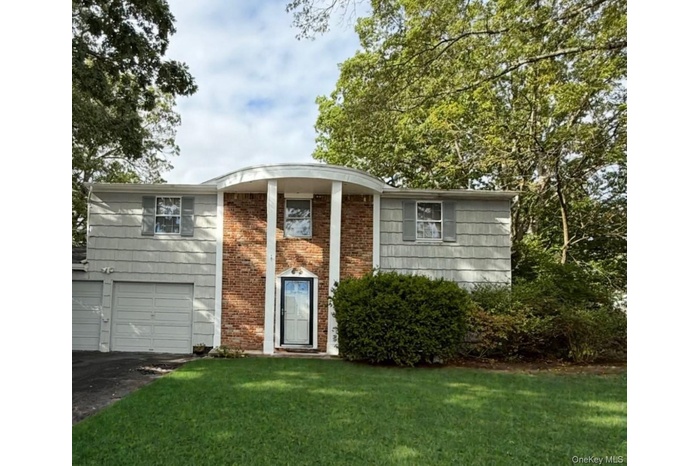View of front of house featuring a front yard, driveway, a garage, and brick siding