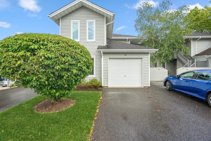 View of front of property with an attached garage, asphalt driveway, and a shingled roof