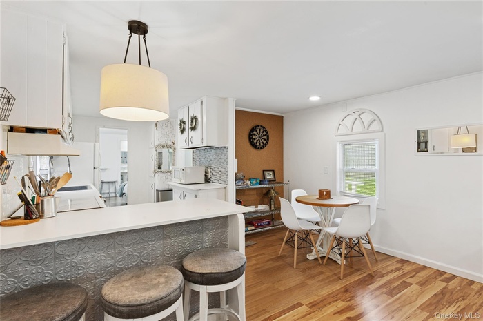 Kitchen with white cabinets, tasteful backsplash, hanging light fixtures, a peninsula, and light countertops