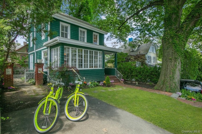 American foursquare style home featuring a front lawn, a gate, and a sunroom