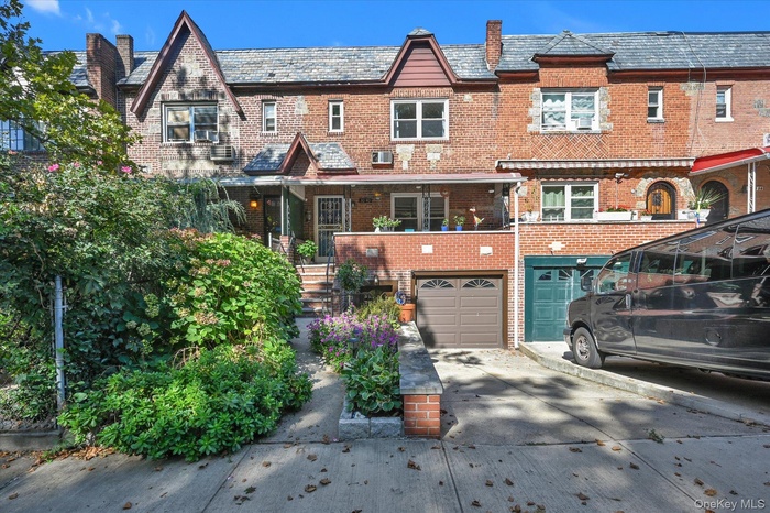 Back of property with brick siding, a high end roof, driveway, a porch, and an attached garage