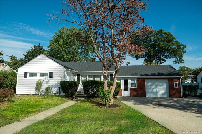 Ranch-style house with driveway, a front lawn, a garage, and covered porch
