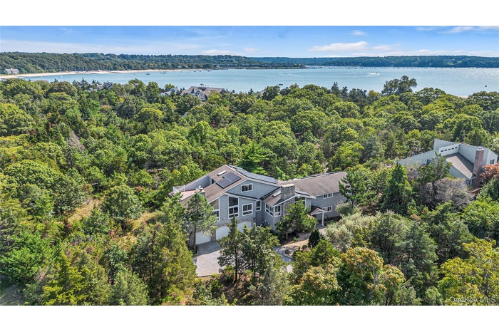 Drone / aerial view of a heavily wooded area and a large body of water