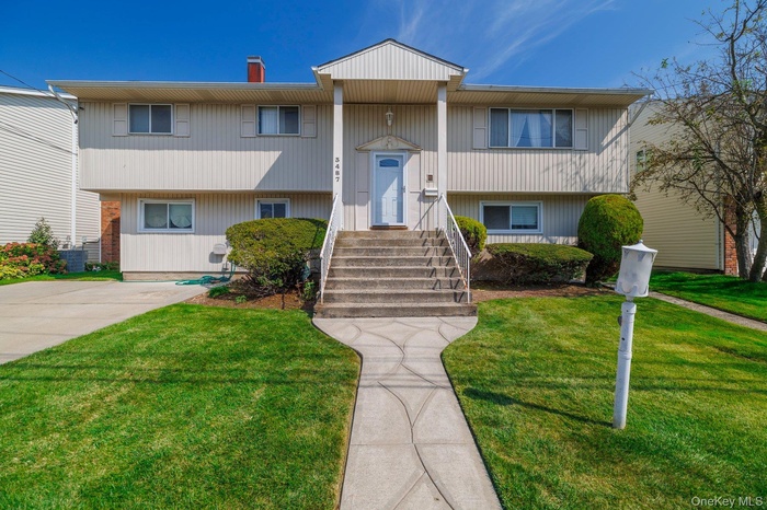 Raised ranch featuring a chimney and a front lawn