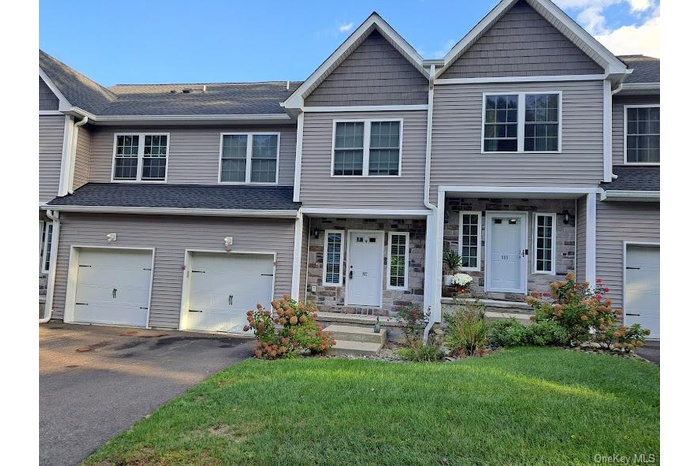 Craftsman house with a front lawn, driveway, an attached garage, and stone siding