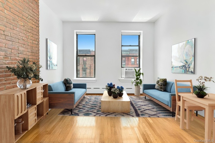 Living room with light wood-style flooring, cooling unit, and brick wall