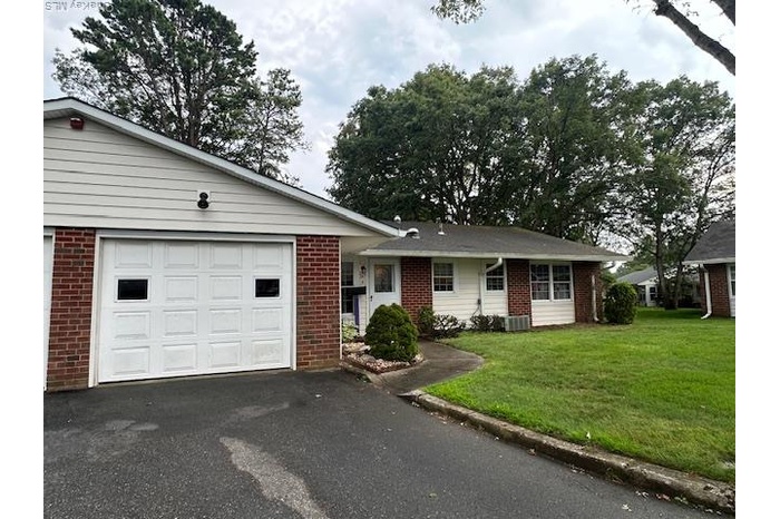 Ranch-style home featuring brick siding, asphalt driveway, a front yard, and a garage